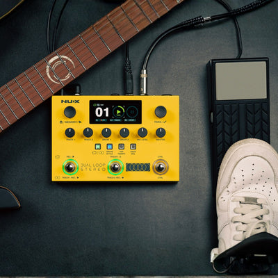 yellow nux dual loop stereo with separate pedal attached next to a guitar